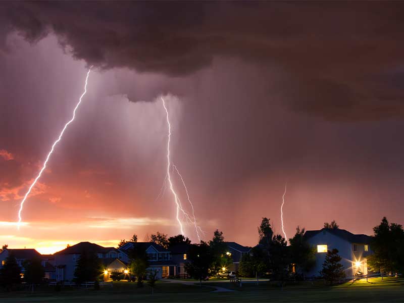 Several lightning strikes over a neighborhood at dusk